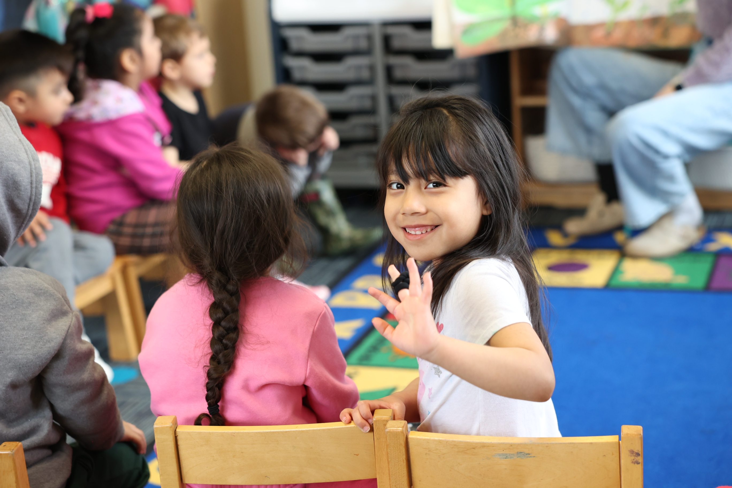 Kid smiling and waving during class
